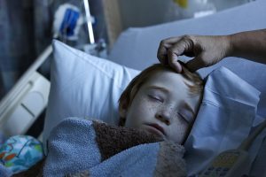 Carrie Windham comforts her son, Rowan, 9, as he sleeps in a hospital room at Methodist Children's Hospital in San Antonio September 2015. Rowan was battling an E. coli infection in his bloodstream, fevers and headaches. Three days earlier, Rowan had participated in the Head for the Cure 5K walk/run for brain cancer research.