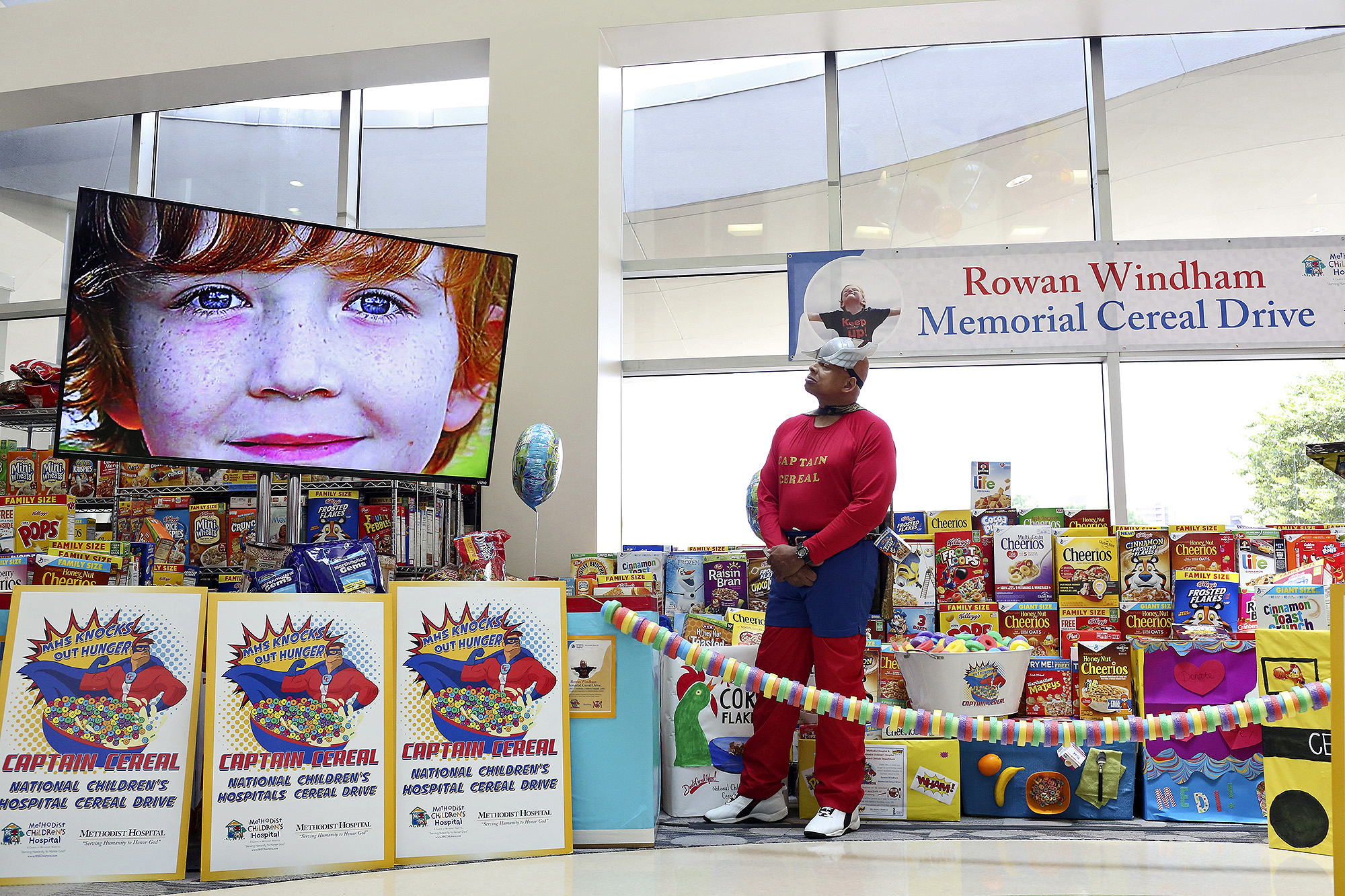 Capt. Cereal watches a video featuring photos of Rowan during the Rowan Windham Memorial Cereal Drive presentation at Methodist Children's Hospital on June 9, 2017.
